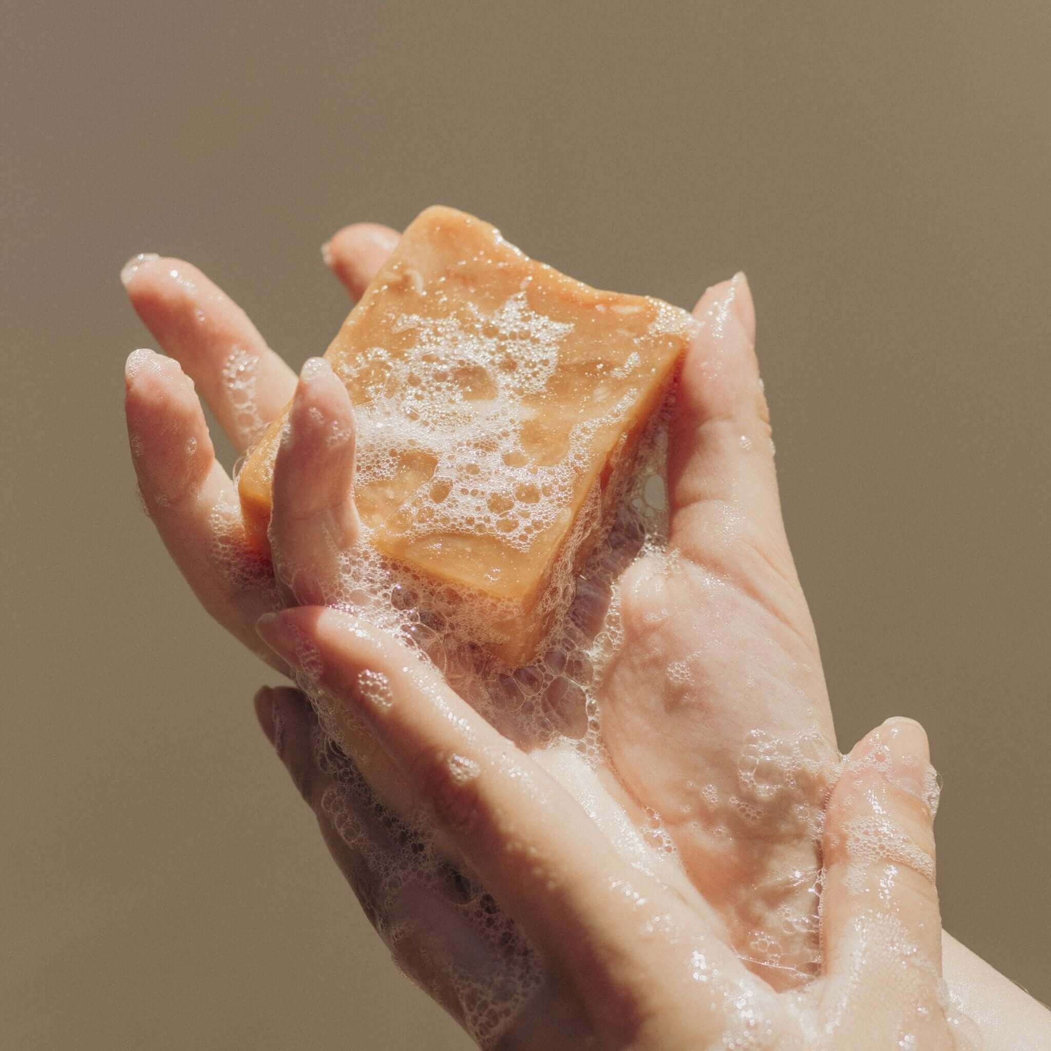 Soapy hands being cleaned with soap bar